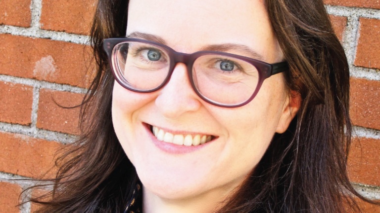 Cropped headshot of Kathryn Brackney in front of a brick wall.