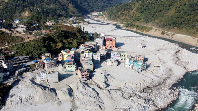 Aerial view of a river valley with damaged buildings half-buried in mud and debris