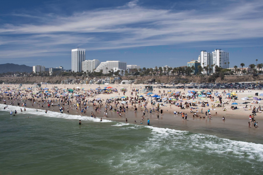 Aerial view off the coast of Santa Monica showing a crowded beach with the city skyline in the background.